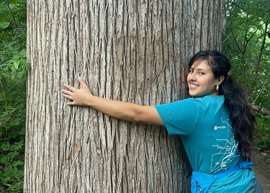 Laisha Alvarado hugs a beautiful towering tree at Onion Creek Metropolitan Park, her arms unable to fully stretch around the trunk.